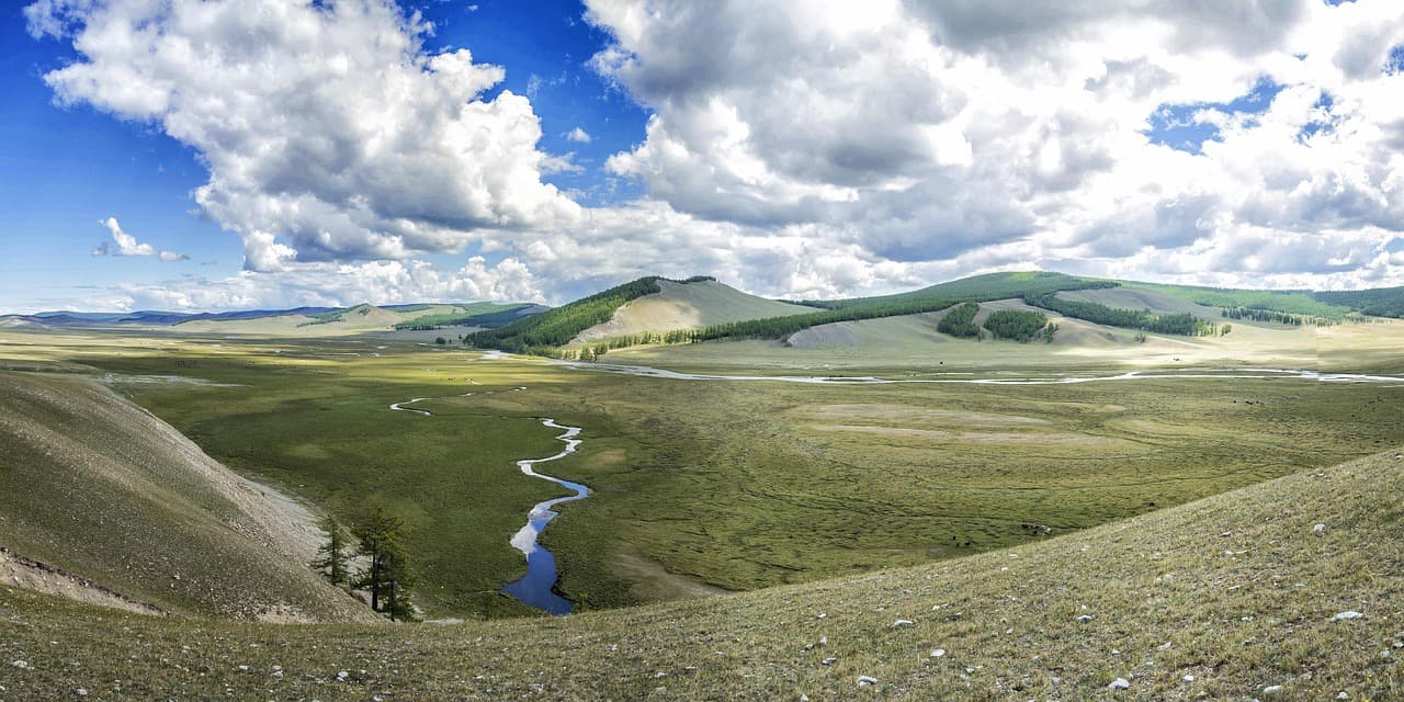A river winding through a wide green valley under clouds, Mongolia