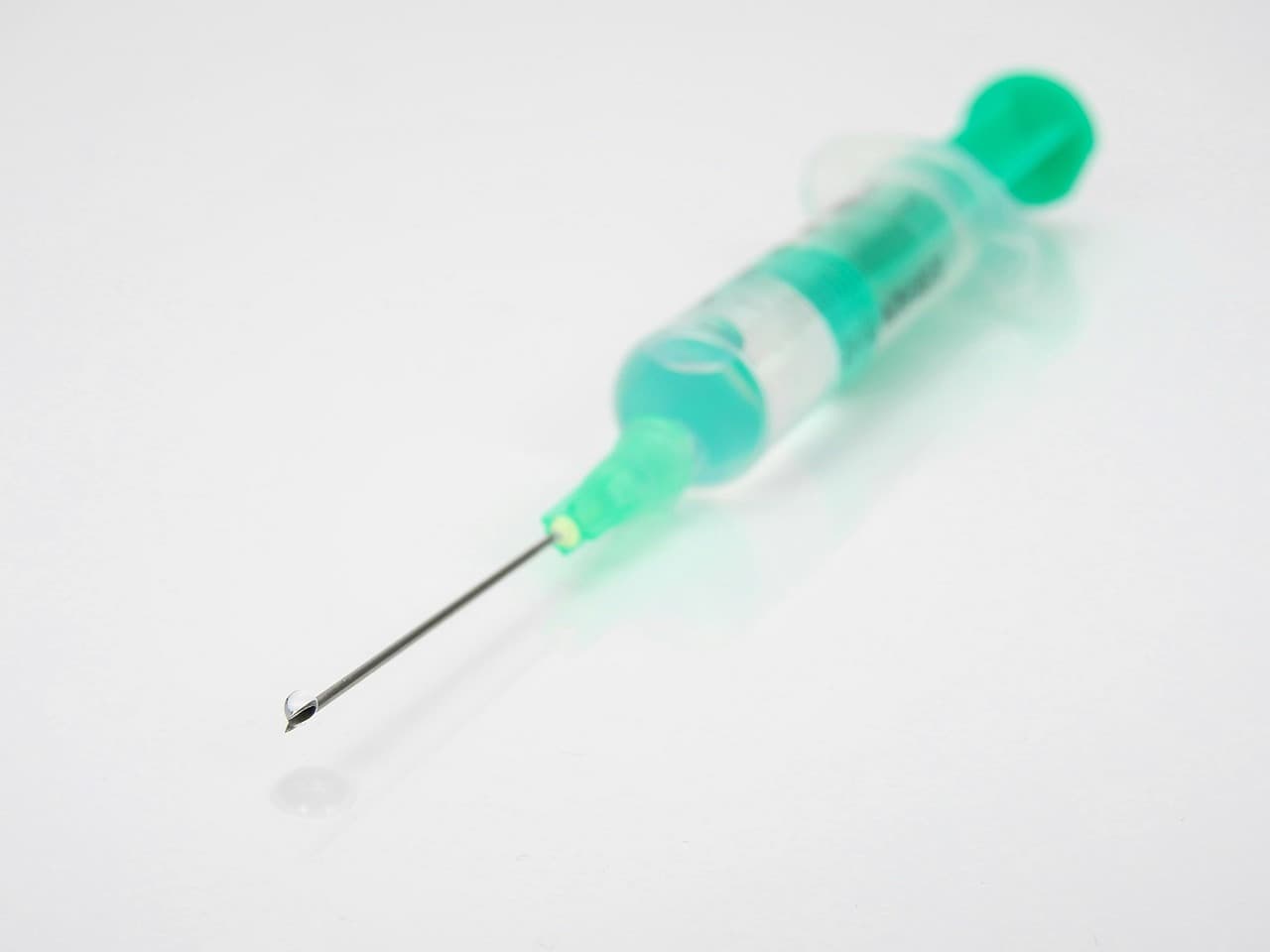 A syringe with a drop on the tip of its needle